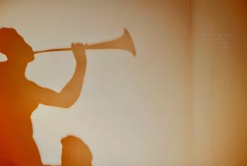 Yellow-toned shadow of a person playing a horn