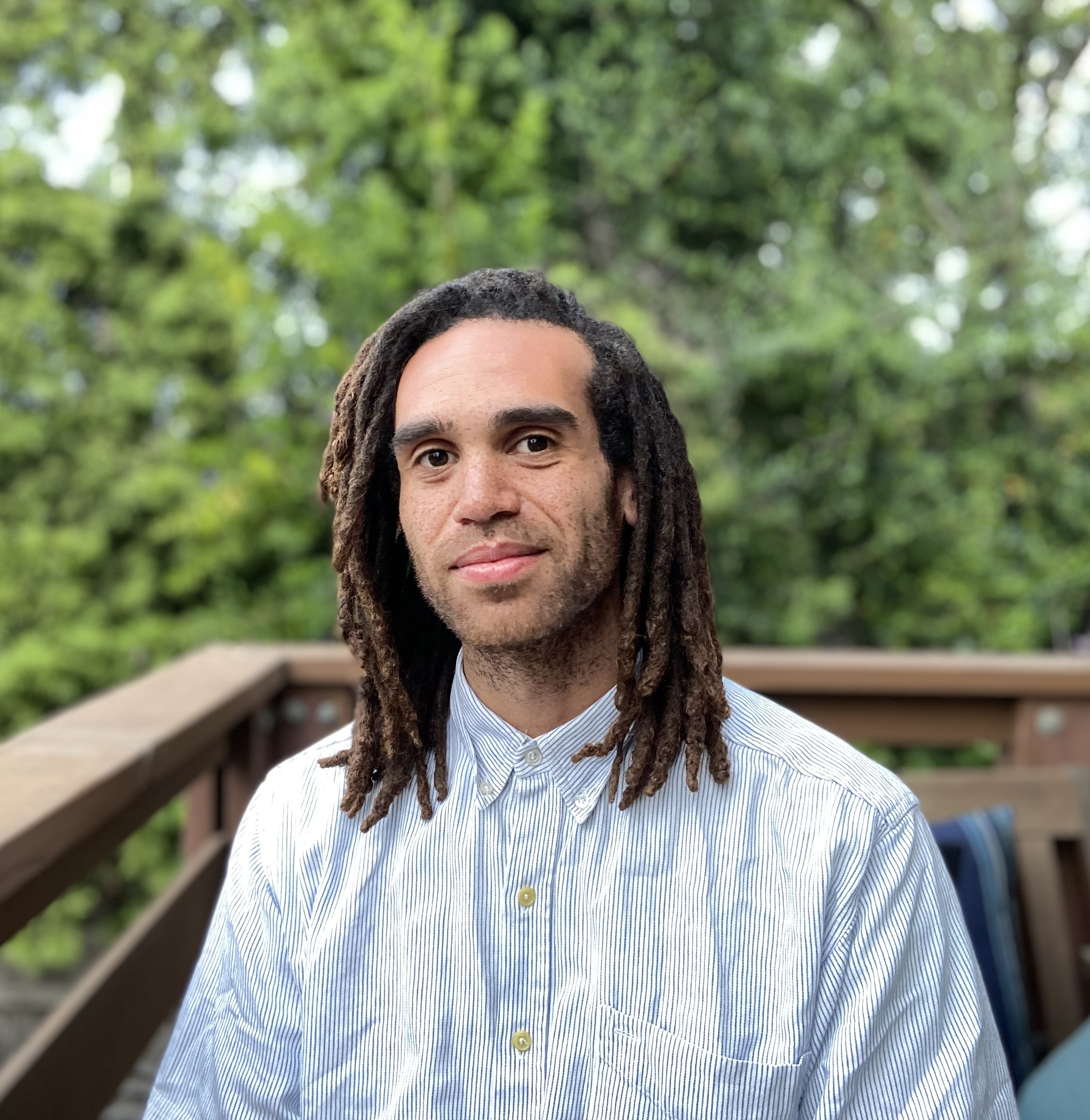 Man in front of trees smiling slightly