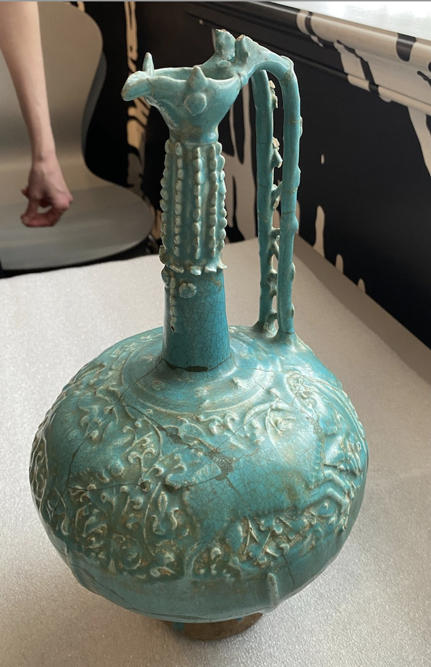 turquoise colored pitcher with long neck and decorative carvings