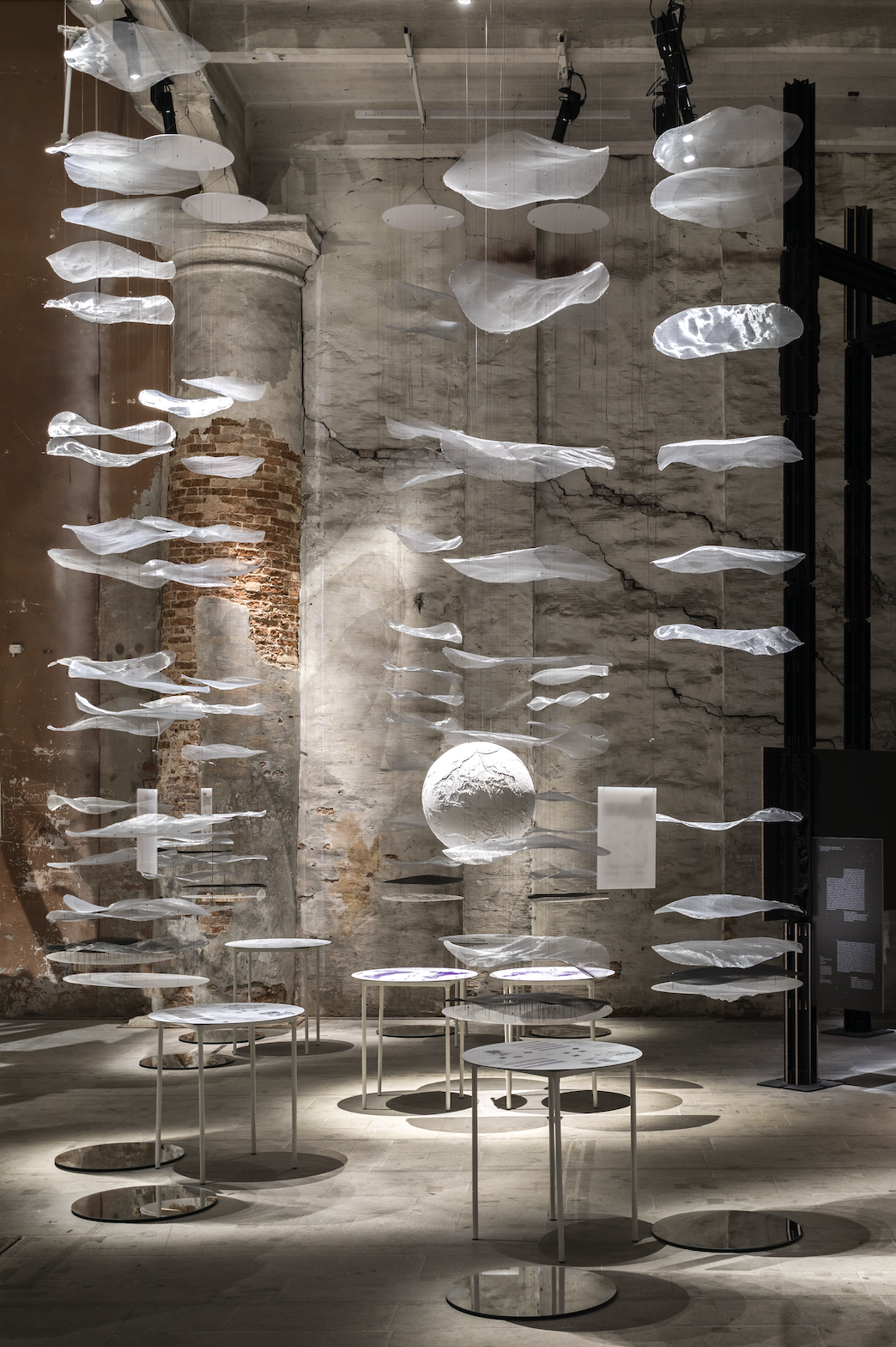 floating white discs of fabric suspended in a cement walled room
