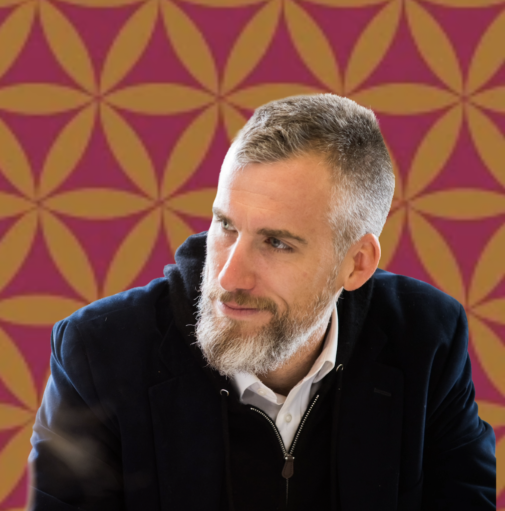 head shot of Tyler Denmead with beard and black coat