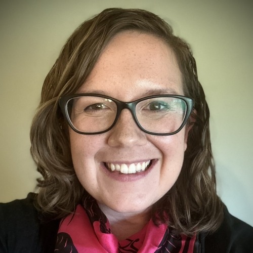 Woman in front of green background wearing black glasses and a pink scarf