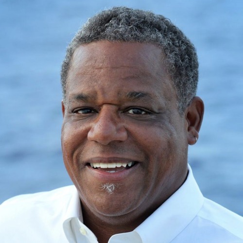 Man, smiling in white shirt in front of blue background