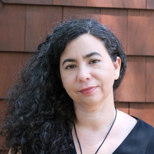 Woman with black hair in black shirt in front of a brown backgrounf
