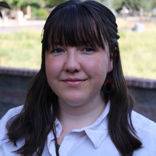 Woman with straight brown hair in white shirt smiling slightly
