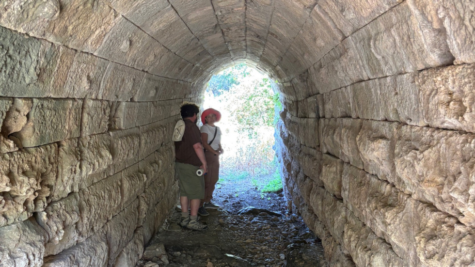 2 figures in ancient stone tunnel